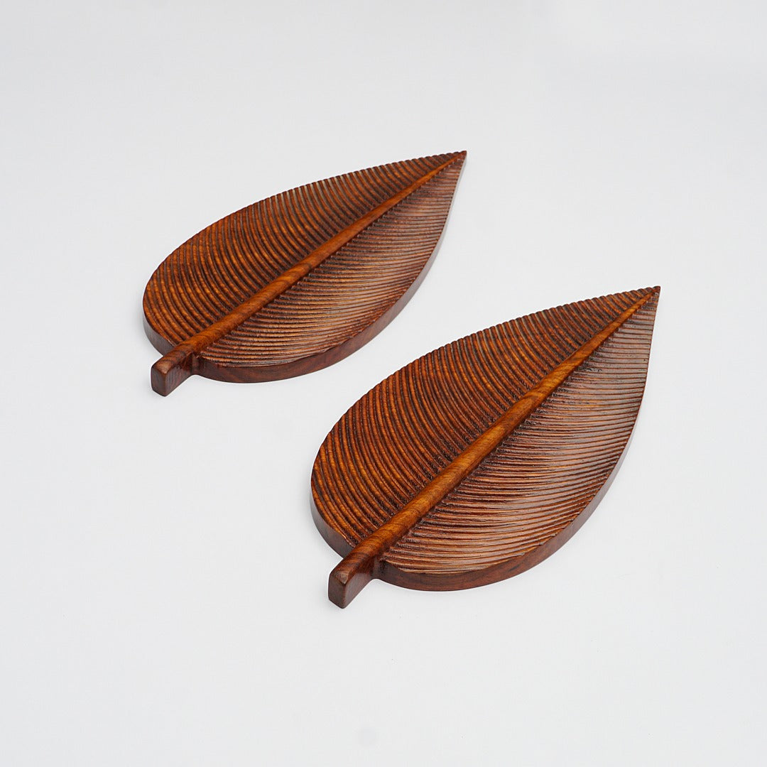 Two brown leaf-shaped trays with raised vein details on a white background