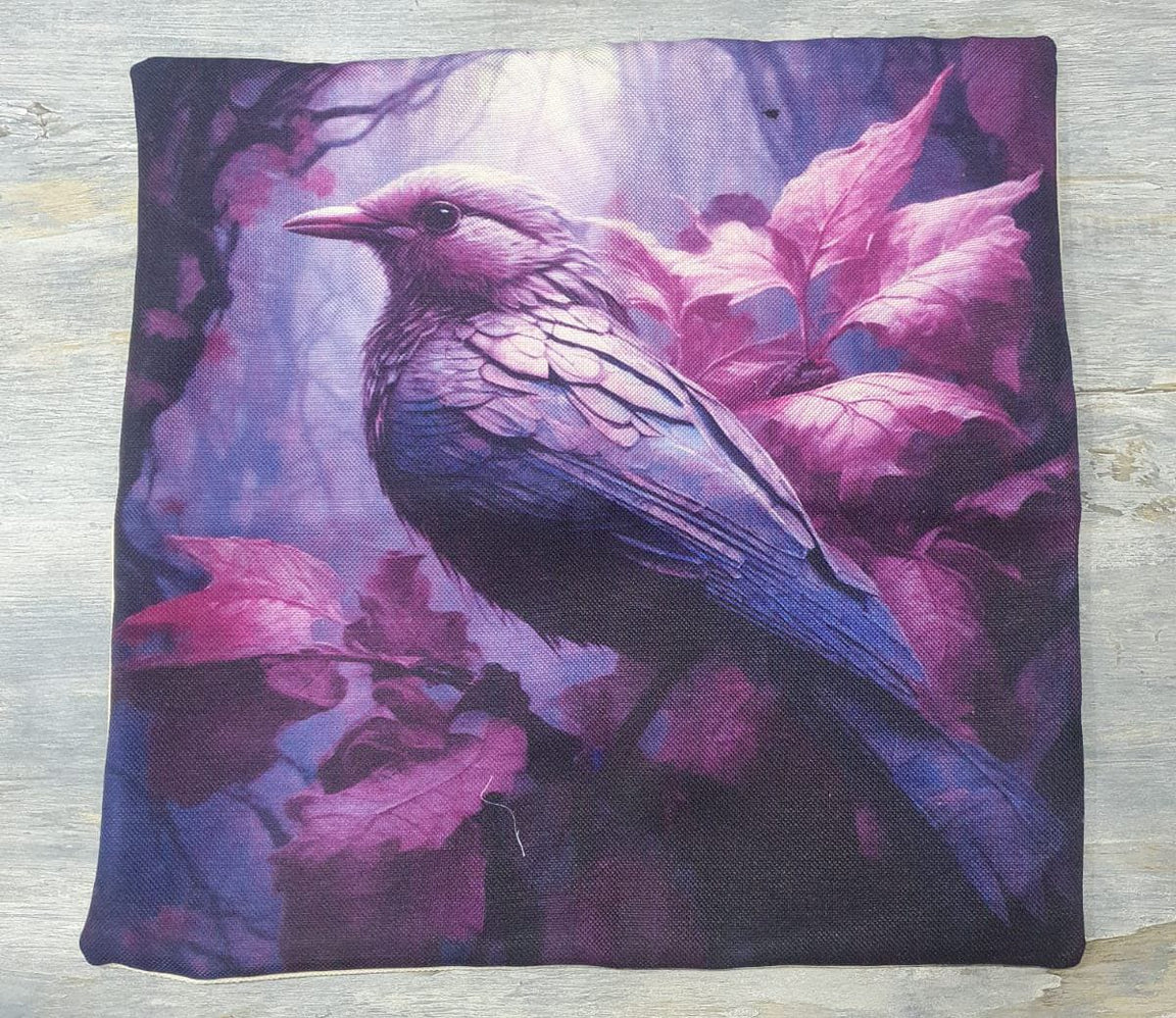 Cushion cover laid flat with a purple bird among pink and purple leaves.