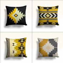 Four mustard, black, grey and cream cushion covers with bold geometric motifs.