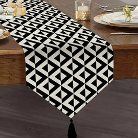 Black and white triangular geometric table runner with a tasselled end.