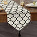 White table runner with black trellis lines and a tasselled end.