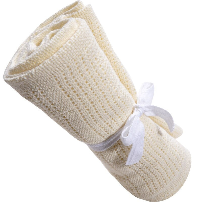 Rolled cream cellular blanket tied with a white ribbon.