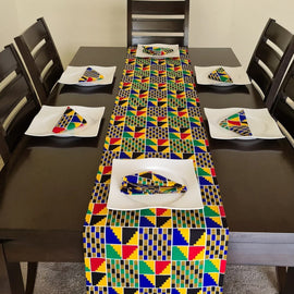 Multicoloured geometric table runner and matching placemats on a dark table.
