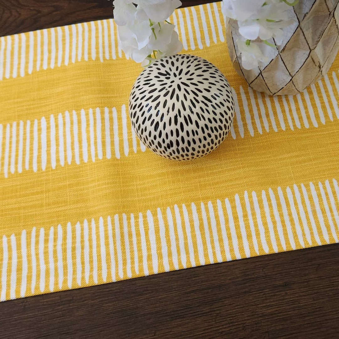 Close view of a yellow and white striped table runner beneath decorative vases.