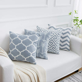 Grey and white geometric cushion covers arranged on a white sofa.
