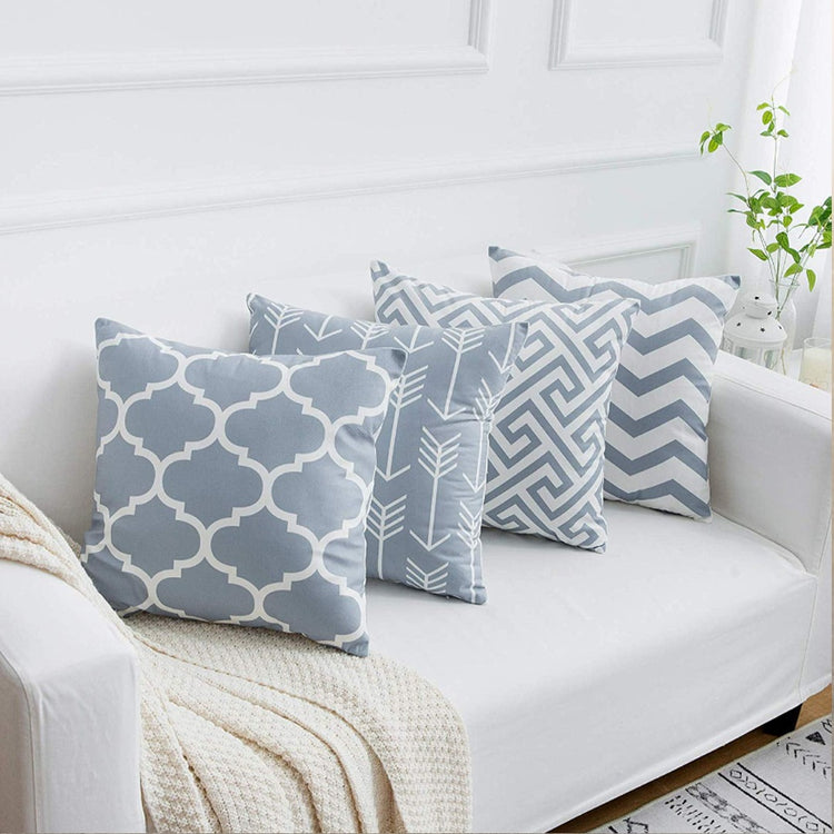 Grey and white geometric cushion covers arranged on a white sofa.