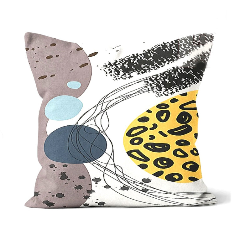 Cushion cover with yellow spots, grey and blue shapes and sweeping black marks.