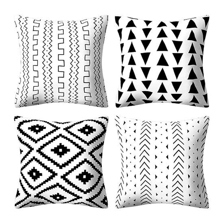 Four white cushion covers with black line, triangle, diamond and dot patterns.