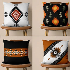 Four black, white and rust geometric cushion covers displayed on wooden chairs.