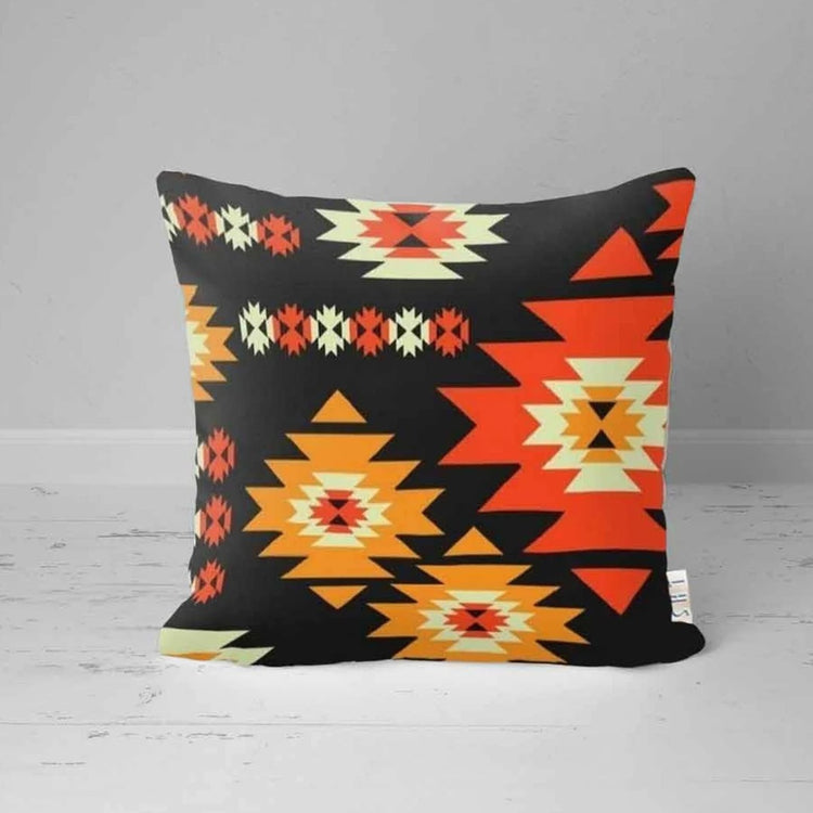 Black cushion cover with orange and cream stepped motifs and small floral shapes.