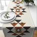 Cream table runner with brown, orange and black geometric motifs.