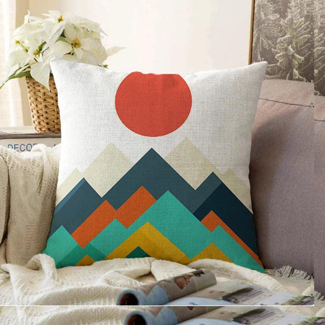 Cream cushion cover with a red sun above teal, orange and mustard mountains.