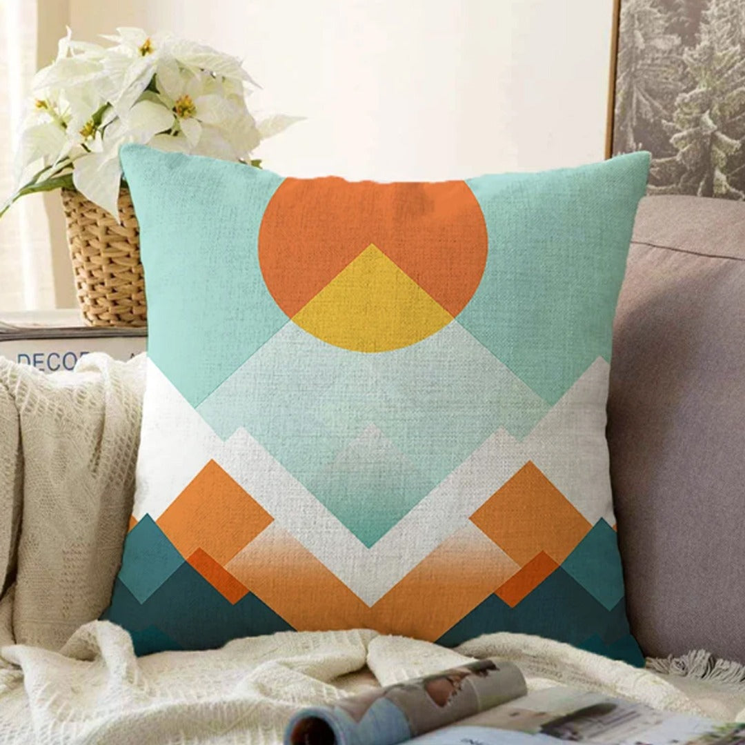 Cushion cover with an orange sun and layered teal, cream and orange mountain shapes.