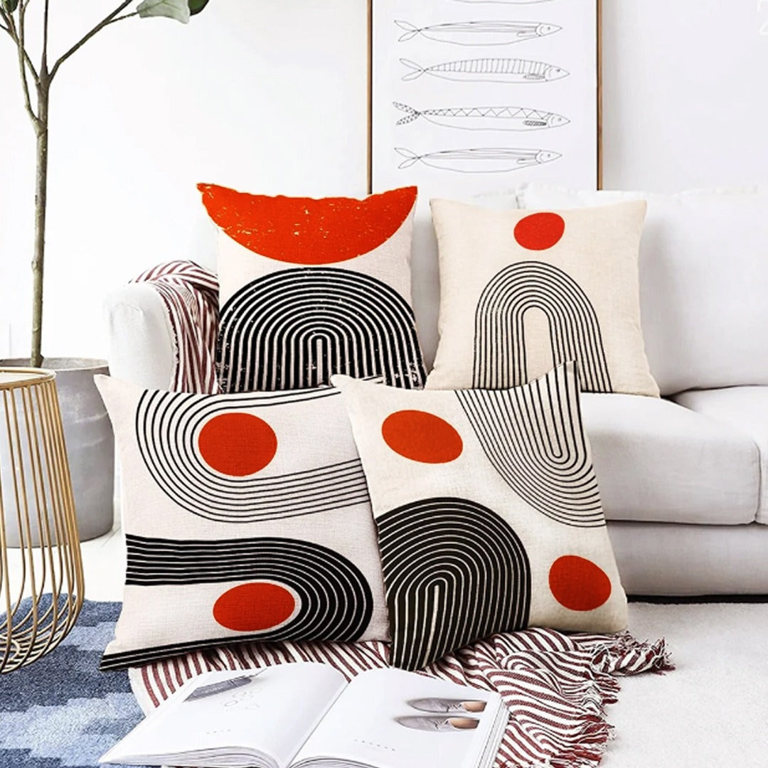 Cream cushion covers with black curved lines and orange circles arranged together.