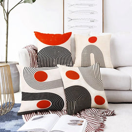 Cream cushion covers with black curved lines and orange circles arranged together.