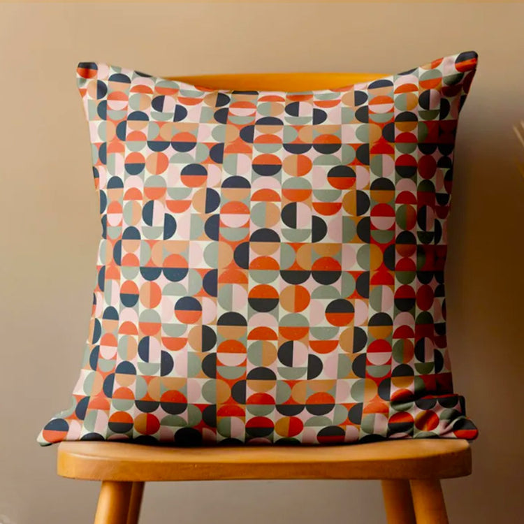 Cushion cover with small orange, grey, blue and cream circular geometric shapes.