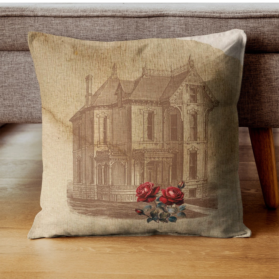 Beige cushion cover with a vintage house illustration and red roses near the base.