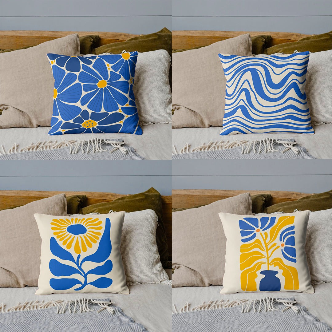 Four blue, yellow and cream cushion covers with floral and wavy designs on a sofa.
