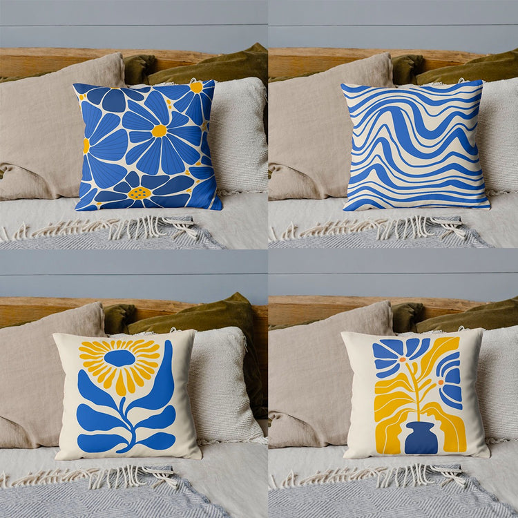 Four blue, yellow and cream cushion covers with floral and wavy designs on a sofa.