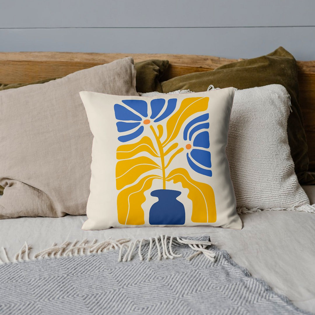 Cream cushion cover with blue and yellow abstract botanical shapes.