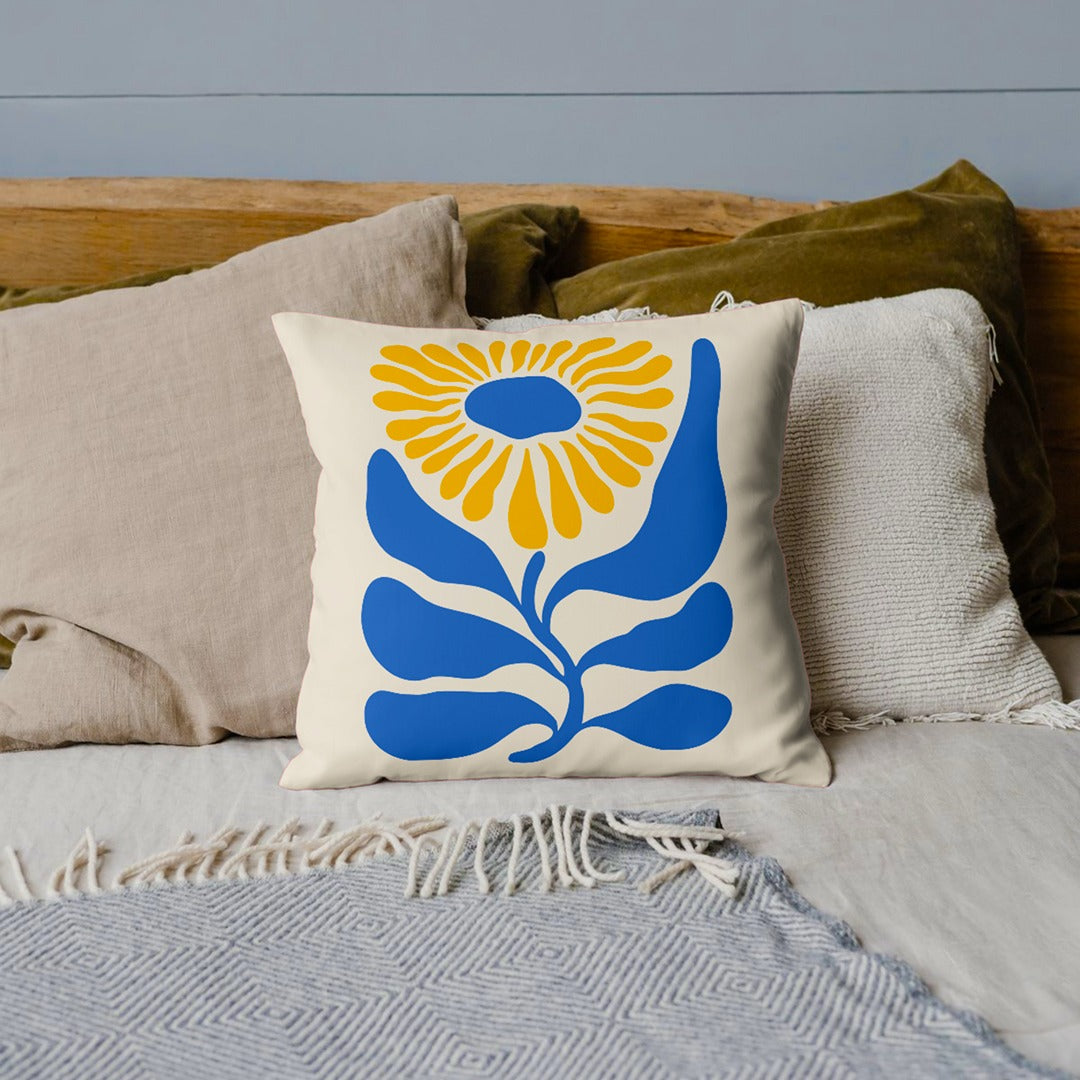 Cream cushion cover with a large blue and yellow flower and blue leaves.