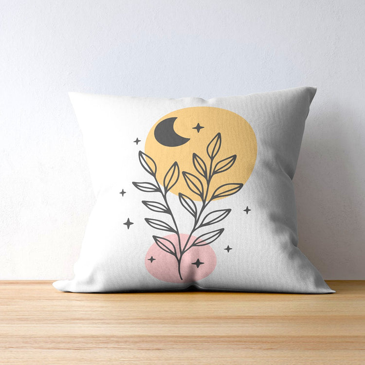 White cushion cover with black leaves, a crescent moon and yellow and pink circles.