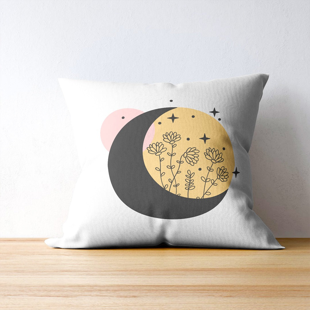 White cushion cover with delicate flowers over overlapping black, yellow and pink circles.