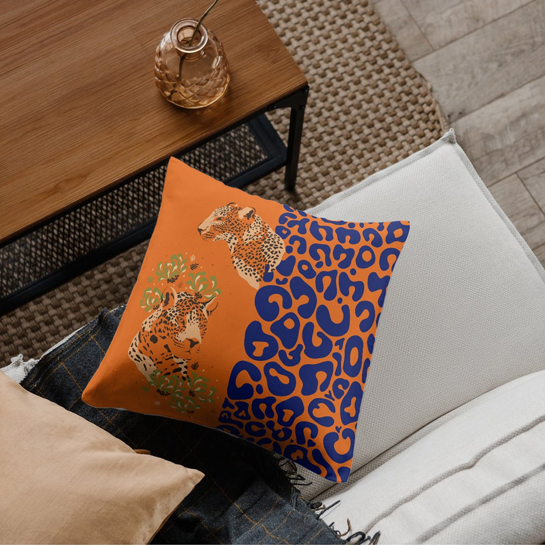 Orange cushion cover with two leopard portraits, small flowers and a blue leopard-spot panel