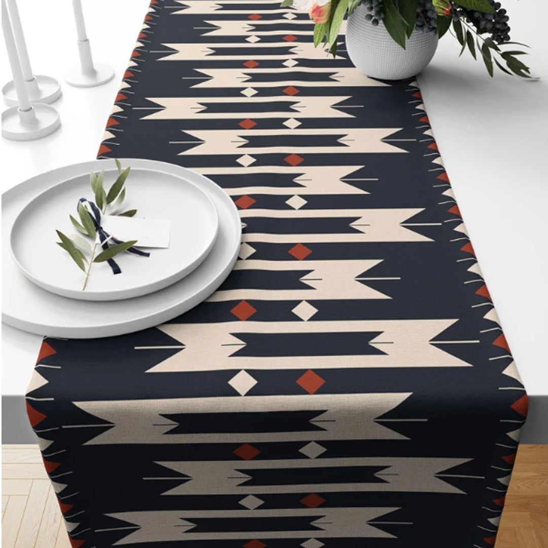 Black table runner with cream stepped motifs and small orange accents.
