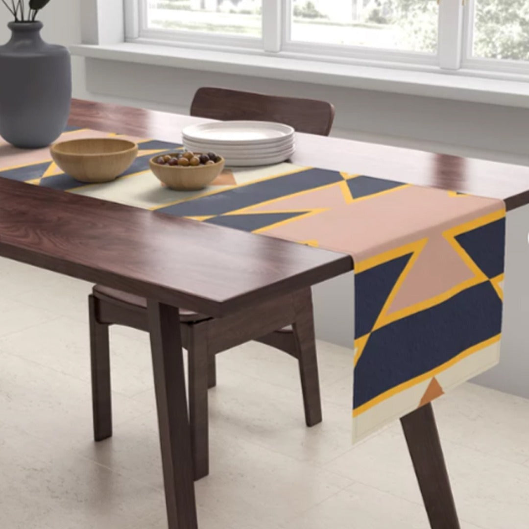 Navy, peach and mustard geometric table runner draped over a dark wooden table.