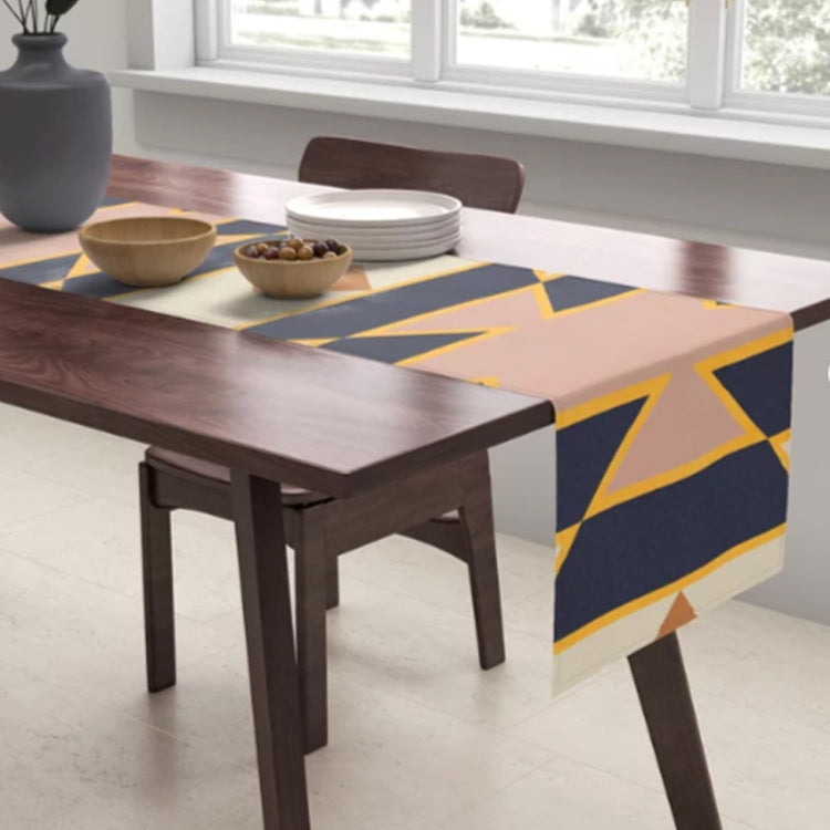 Navy, peach and mustard geometric table runner draped over a dark wooden table.