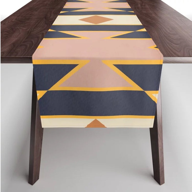 Navy, peach and mustard geometric table runner draped over a dark wooden table.