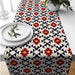 Cream table runner with small red, navy and yellow geometric star motifs.