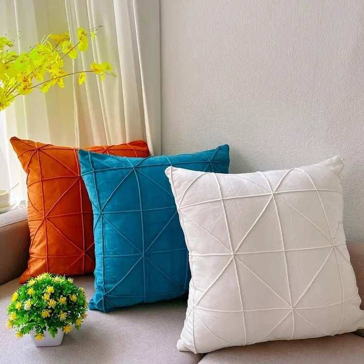 Orange, teal and cream cushion covers with geometric stitched lines displayed together.