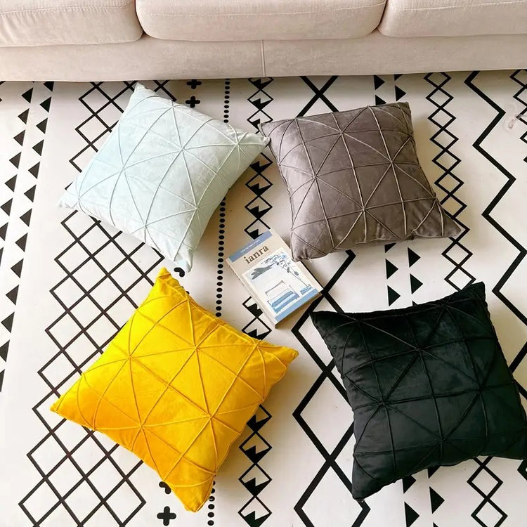 Pale blue, grey, yellow and dark green cushion covers with geometric stitched lines.
