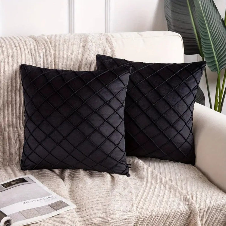 Two black cushion covers with diamond stitching on a sofa.