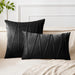 Black square and rectangular cushion covers with angular stitched lines on a bed.