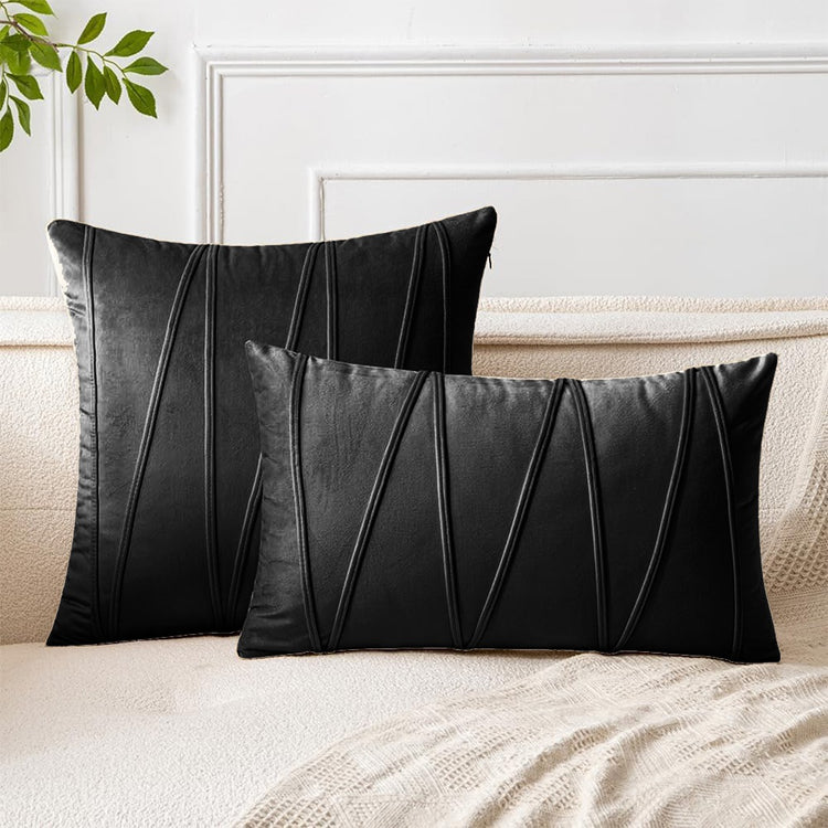 Black square and rectangular cushion covers with angular stitched lines on a bed.