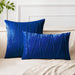 Blue square and rectangular cushion covers with angular stitched lines on a bed.