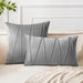 Grey square and rectangular cushion covers with angular stitched lines on a bed.