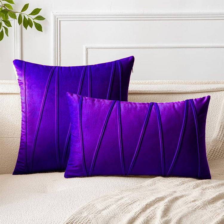 Purple square and rectangular cushion covers with angular stitched lines on a bed.