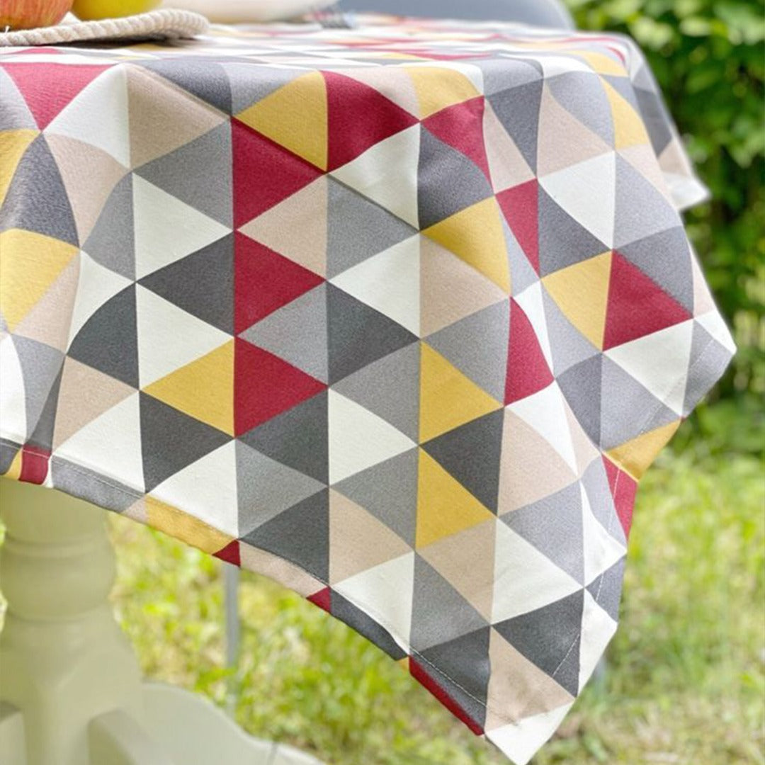 Close view of the draped edge of a multicoloured triangle-pattern tablecloth.