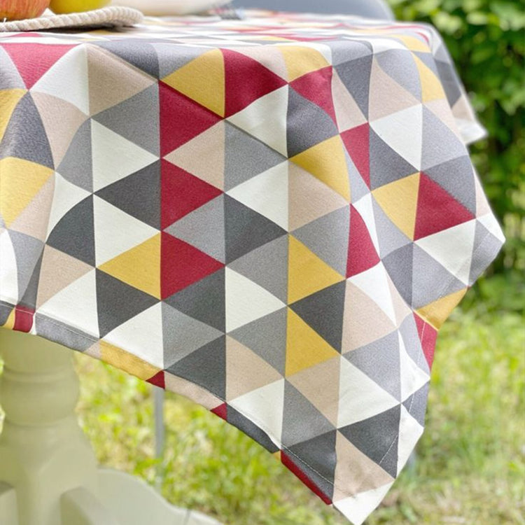 Close view of the draped edge of a multicoloured triangle-pattern tablecloth.