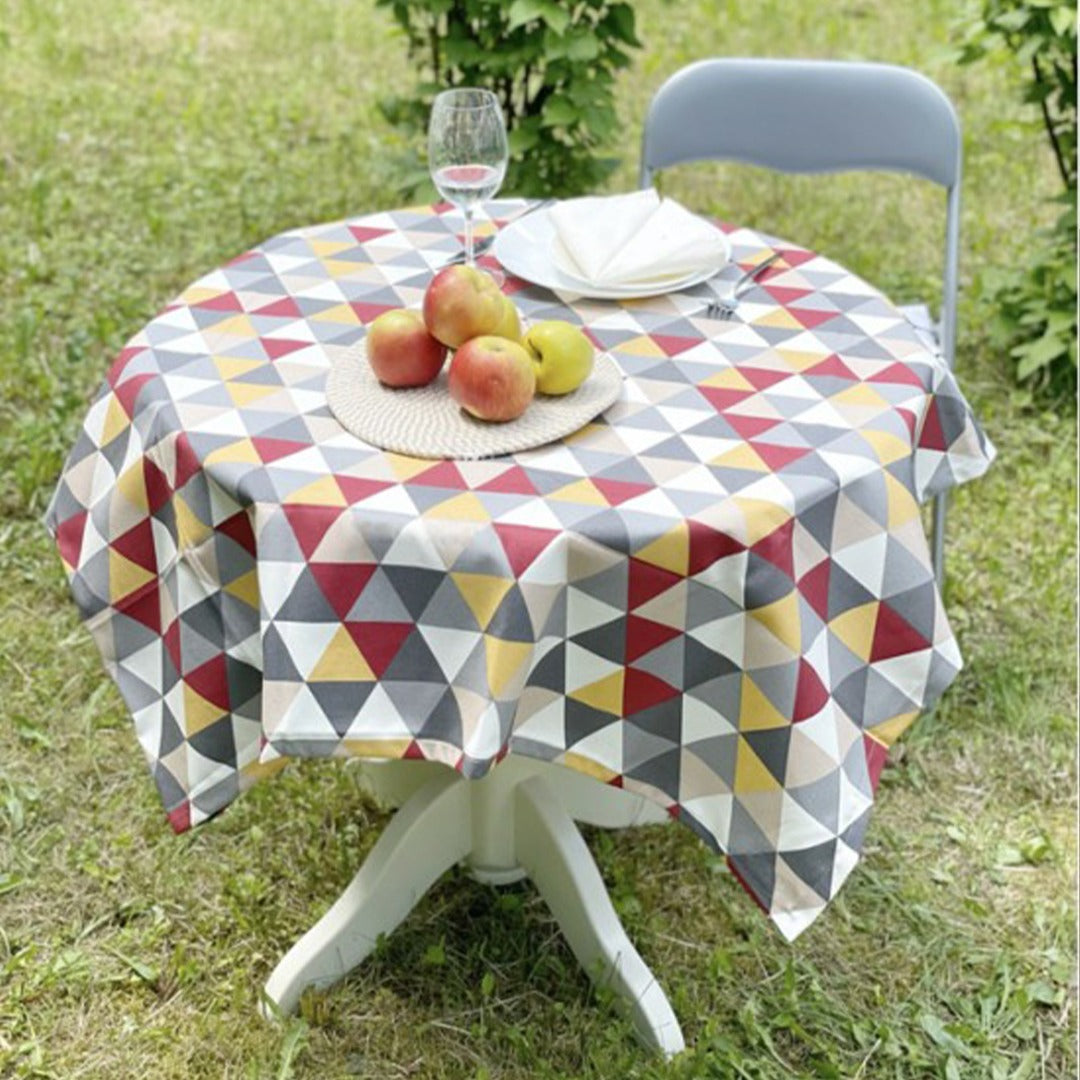Round tablecloth with grey, white, yellow and red geometric triangles.