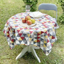 Round tablecloth with grey, white, yellow and red geometric triangles.
