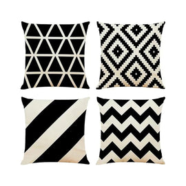 Four black and cream cushion covers with triangles, diamonds, diagonal stripes and zigzags.