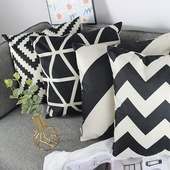Black and cream geometric cushion covers arranged on a dark sofa.