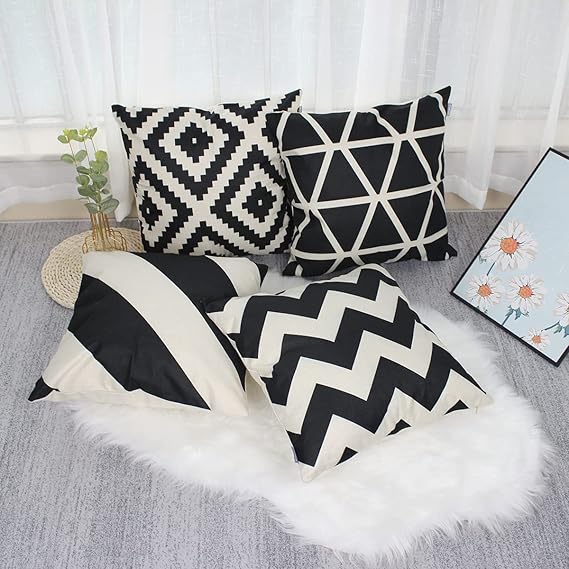 Black and cream striped and geometric cushion covers displayed together on a light rug.