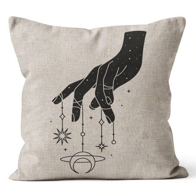 Beige cushion cover with a black hand and dangling stars, moons and planets.
