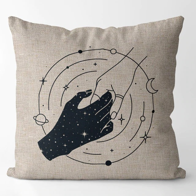 Beige cushion cover with a black hand holding a crescent moon within orbital lines.